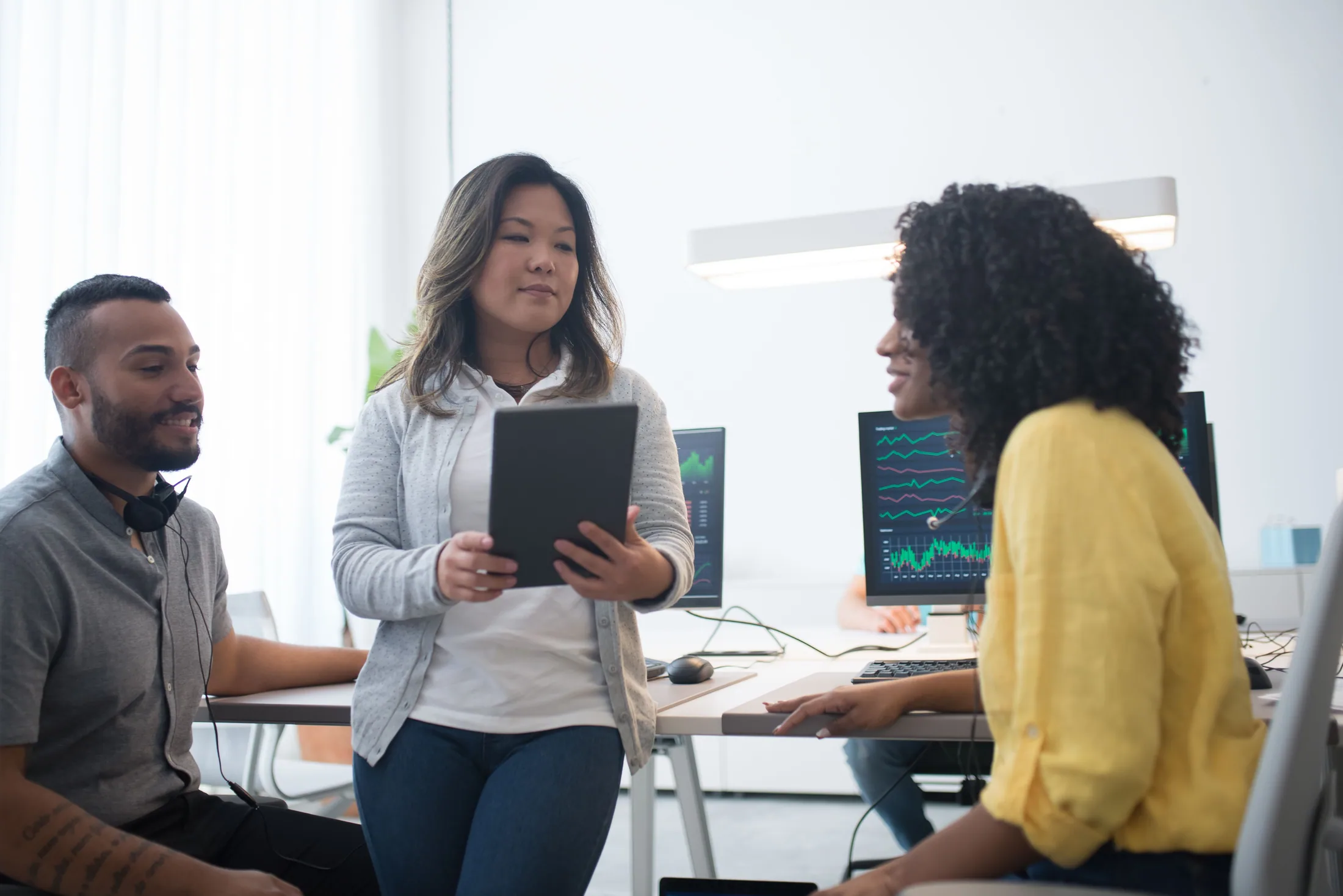 A team collaborating beside screens displaying financial data